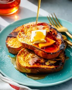 Torrada francesa na Airfryer dourada e macia, coberta com manteiga derretida e calda doce escorrendo.